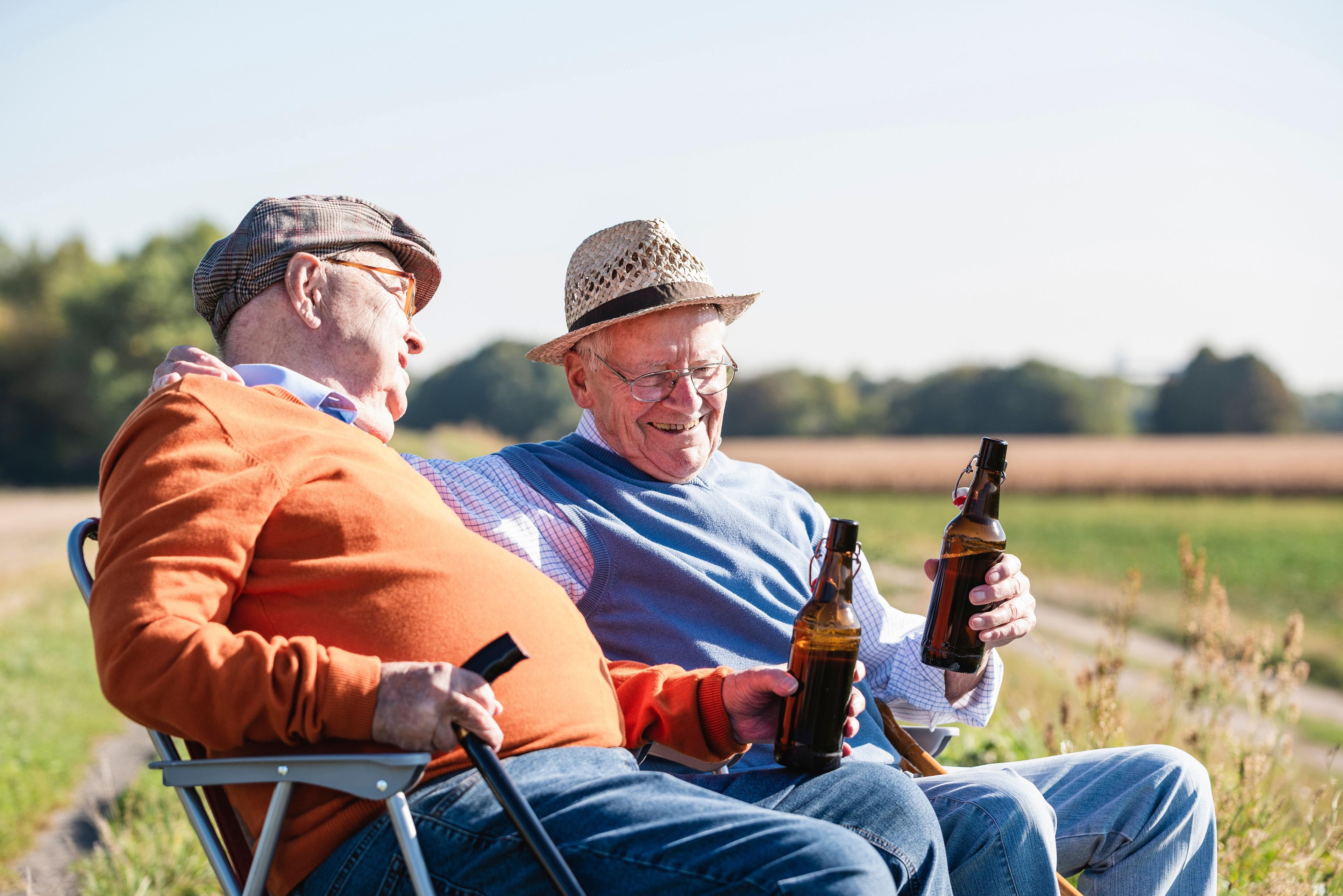 Zwei ältere Männer trinken ein Bier. 