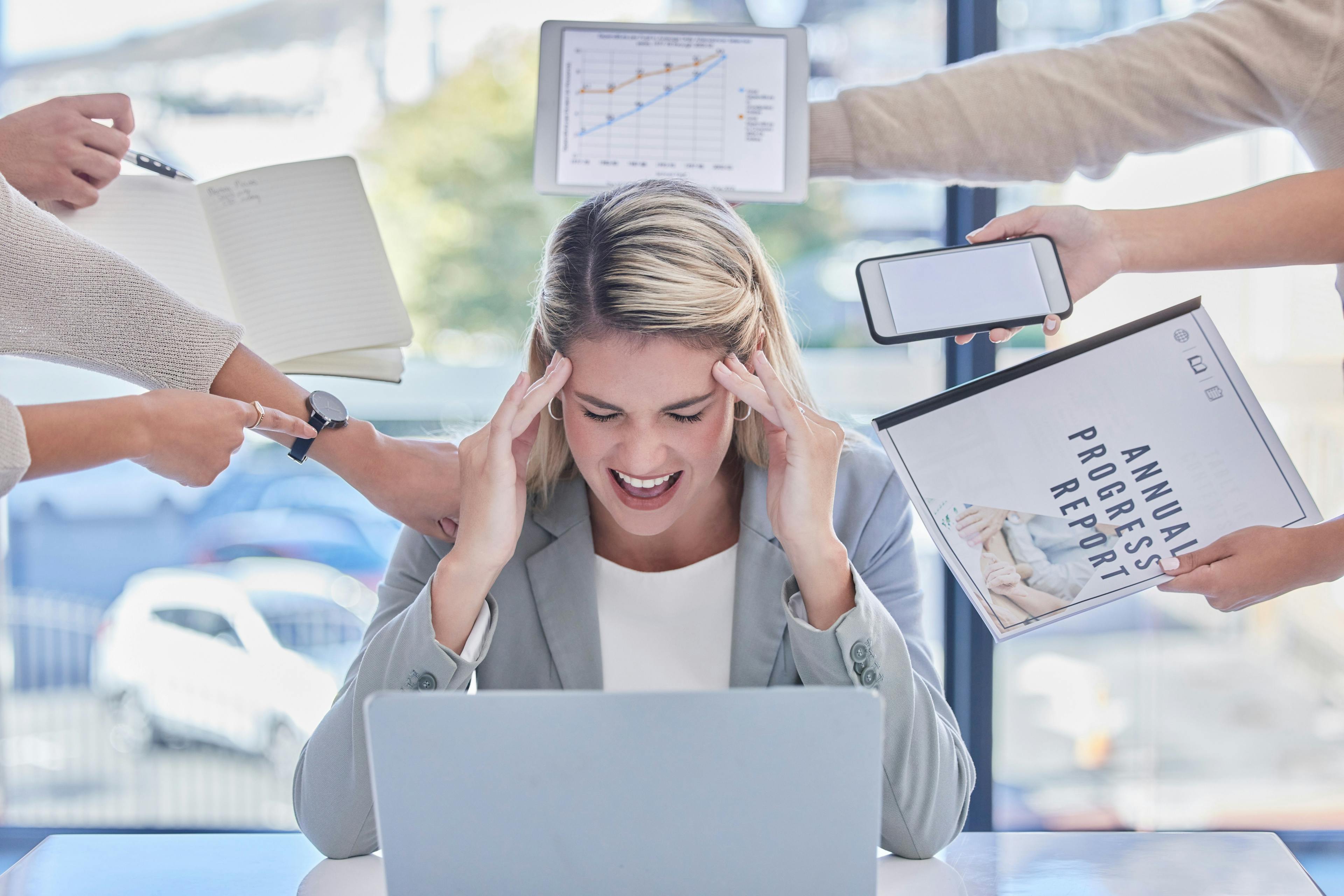 Eine Frau fühlt sich am Arbeitsplatz gestresst durch ihre vielen Aufgaben.