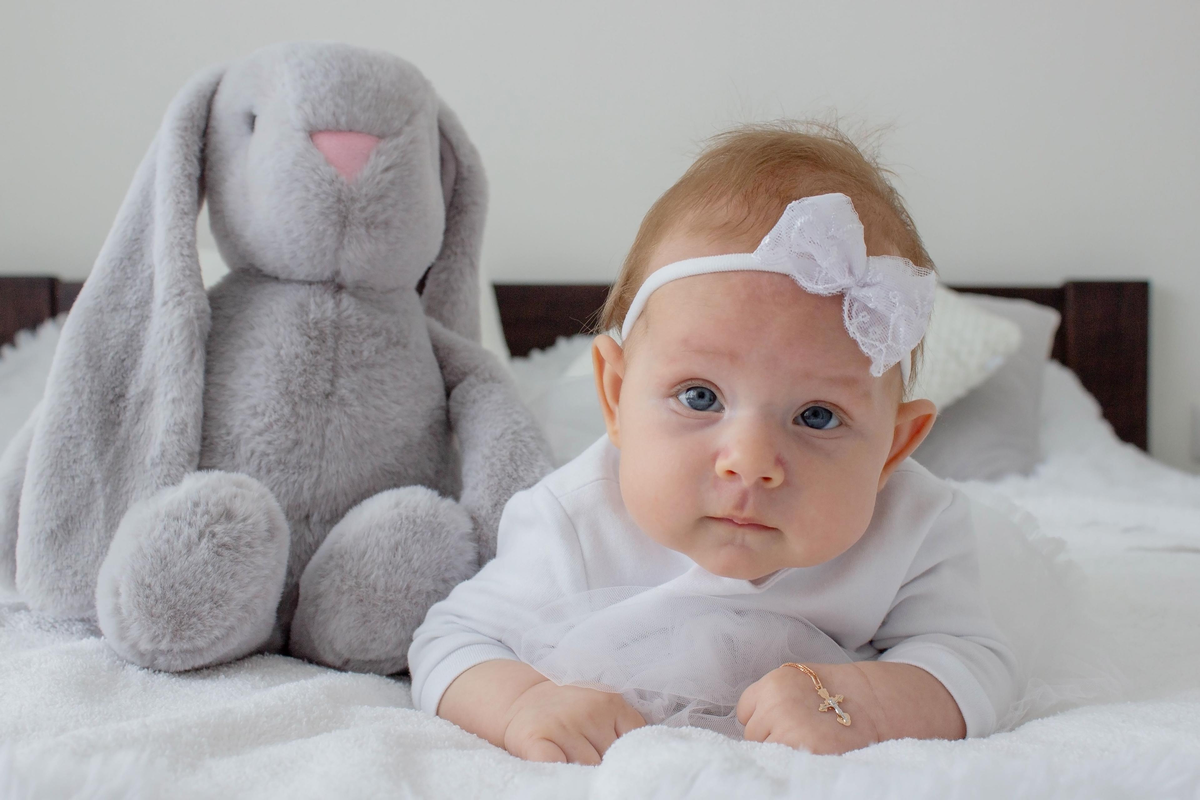 Ein Baby in Taufkleidung mit einem Kreuzanhänger. 