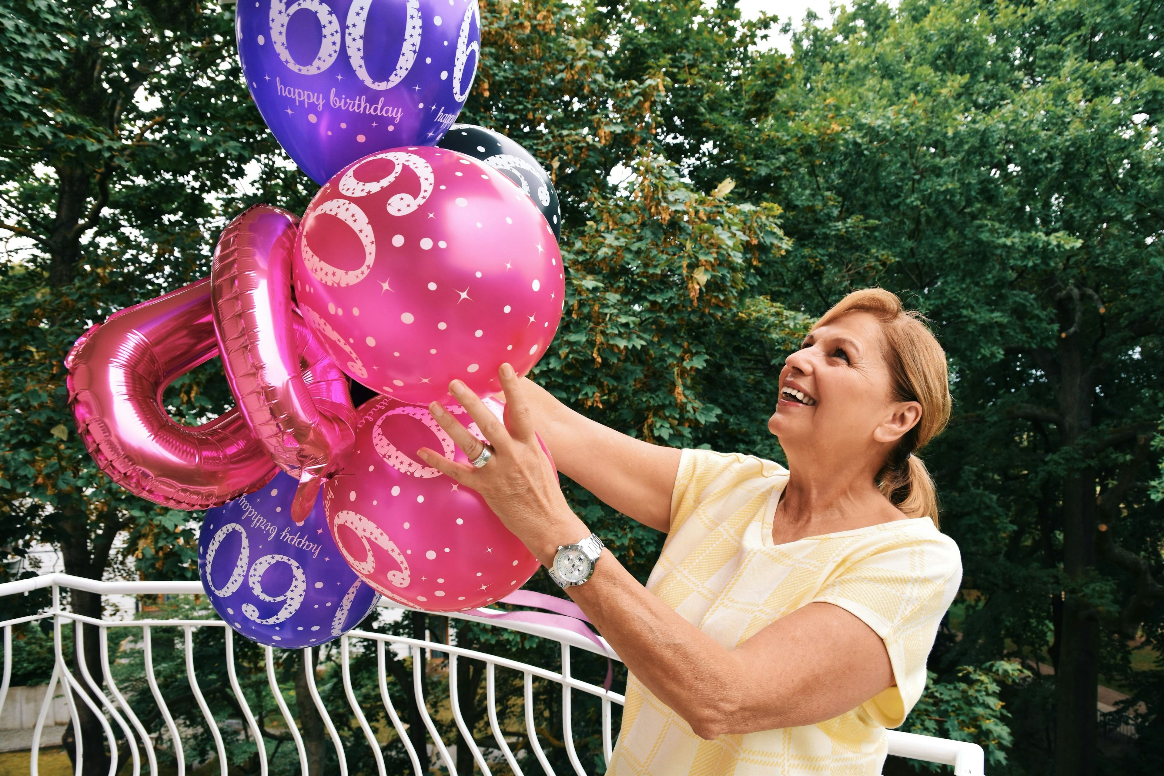 Eine Frau feiert ihren 60. Geburtstag mit Ballonen. 